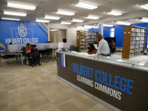 library service desk in gray wood with blue and white letters spelling Hilbert College